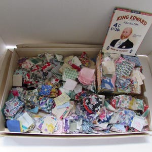 May include: A large collection of small, multi-colored fabric squares stored in a cardboard box. A vintage King Edward Cigarillos box lid featuring a portrait of a man and the text 4 cents, 5 for 20 cents, Made in Florida is attached.