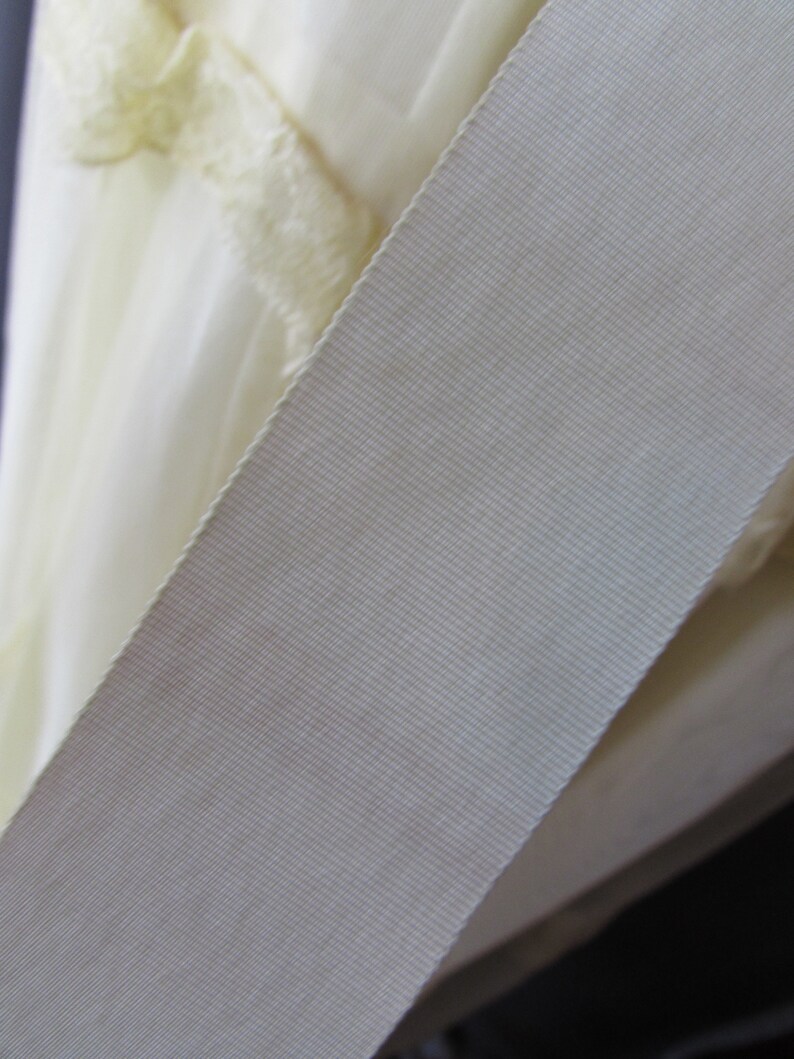 May include: Close-up of a white satin ribbon with a textured surface.