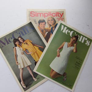 May include: Three vintage fashion magazines, McCall's, McCall's, and Simplicity. The McCall's magazines feature models wearing white and yellow dresses. The Simplicity magazine features a model wearing a white dress and a model wearing a green dress.