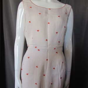 May include: A sleeveless white dress with a scoop neck and a small orange floral pattern.