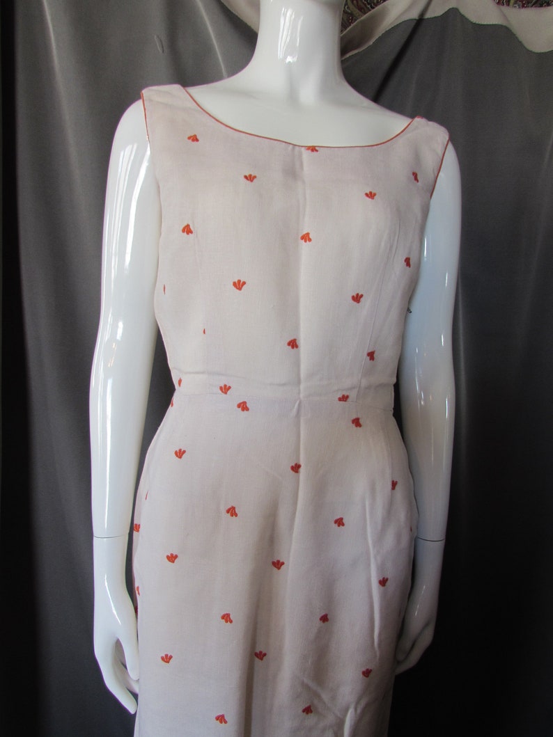 May include: A sleeveless white dress with a scoop neck and a small orange floral pattern.