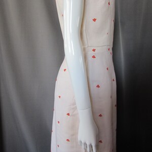 May include: A sleeveless white dress with a red floral pattern. The dress has a scoop neck and a fitted bodice. The dress is made of a lightweight fabric and is perfect for summer.