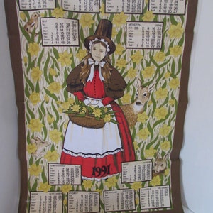 May include: A vintage Welsh calendar for the year 1991. The calendar features a woman in traditional Welsh dress holding a basket of daffodils. The background is a floral pattern with daffodils and green leaves. The calendar is printed on brown paper.