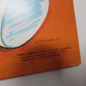 May include: An orange background with a partial illustration in blue and white. The text reads "&copy; 1971 Mattel, Inc." and "BABY TENDER LOVE" is a U.S. registered trademark of Mattel, Inc. for its DOLL. Used under license from Mattel, Inc."