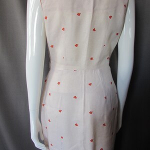 May include: A sleeveless white dress with a scoop neck and a small orange floral pattern.