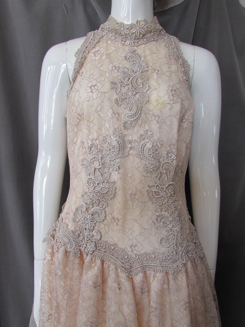 May include: A delicate, off-white lace dress with a high neckline and a fitted bodice. The dress features intricate floral lace patterns and a flowing skirt.