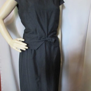 Puede incluir: Un vestido negro sin mangas con un lazo en la cintura.