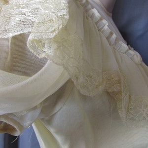 May include: A white sheer top with a lace trim around the neckline and sleeves. The top is made of a lightweight fabric and has a delicate, feminine look.