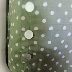 May include: A green dress with white polka dots and a row of white buttons down the front.