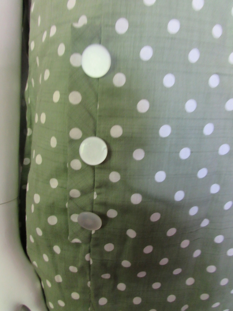 May include: A green dress with white polka dots and a row of white buttons down the front.