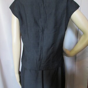Puede incluir: Un vestido negro sin mangas con un corpi&ntilde;o ajustado y una falda completa. El vestido tiene una cremallera en la espalda.