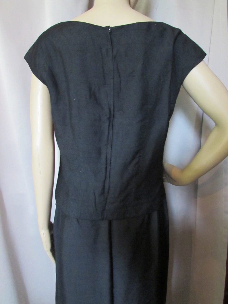 Puede incluir: Un vestido negro sin mangas con un corpi&ntilde;o ajustado y una falda completa. El vestido tiene una cremallera en la espalda.