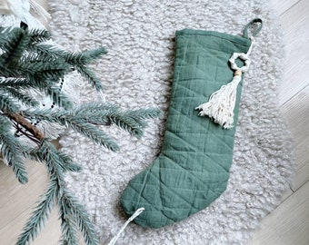 May include: A green quilted Christmas stocking with a white tassel and a wooden ring ornament.