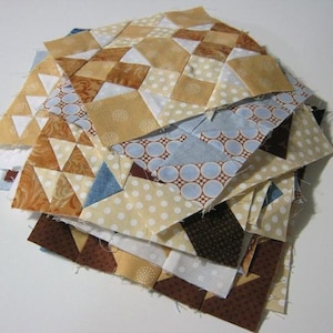 May include: A stack of fabric squares in various patterns and colors, including brown, white, blue, and yellow. The squares are arranged in a random order, with some squares overlapping others.