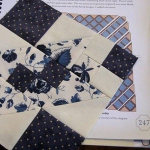 May include: A close-up of a quilt in progress, featuring a patchwork design with navy blue and cream-colored fabrics. Some squares have a polka dot pattern, while others display floral prints. The text "Queen-Size Sampler Quilt" is visible.