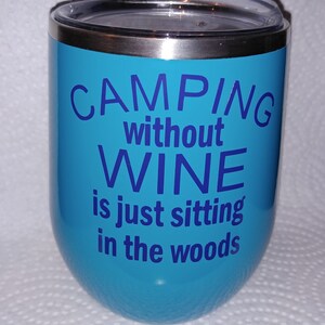 May include: A turquoise stainless steel tumbler with a silver lid. The tumbler has the text "Camping without wine is just sitting in the woods" printed in blue.