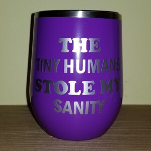 May include: Purple stainless steel wine tumbler with a silver vinyl design that reads "THE TINY HUMANS STOLE MY SANITY".
