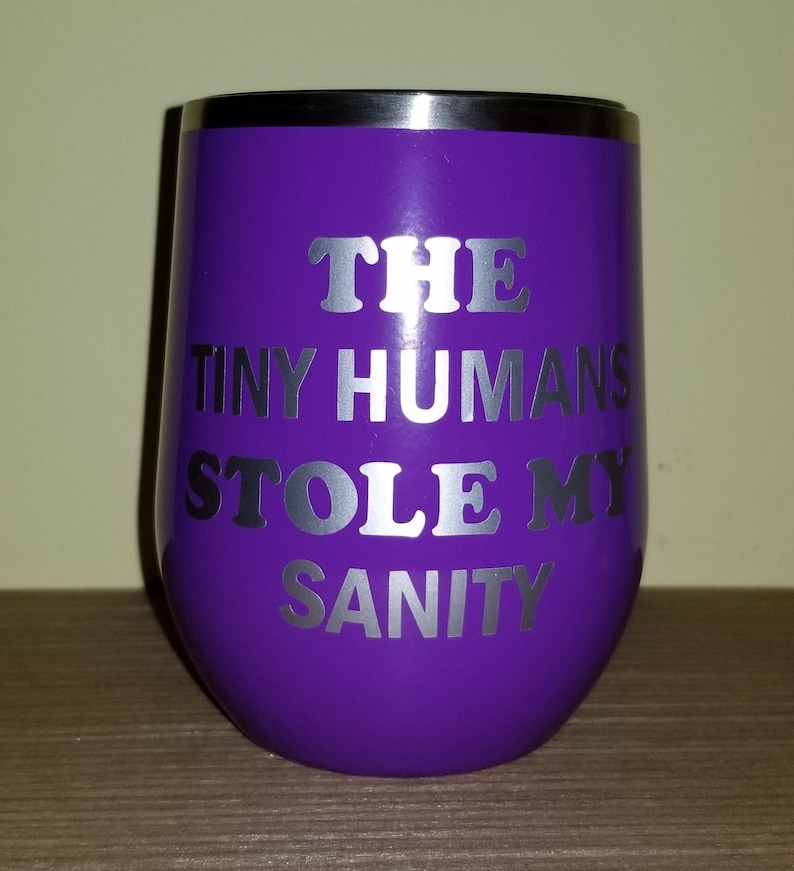 May include: Purple stainless steel wine tumbler with a silver vinyl design that reads "THE TINY HUMANS STOLE MY SANITY".