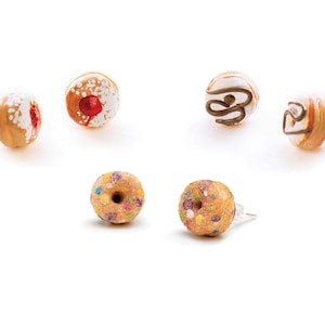 May include: A set of six donut-shaped earrings. The earrings are made of polymer clay and feature different toppings, including sprinkles, chocolate, and a cherry.