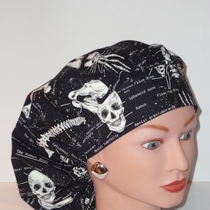 May include: Black and white skull and skeleton print scrub hat with anatomical labels. The hat is made of a soft, comfortable fabric and is perfect for nurses, doctors, and other healthcare professionals.