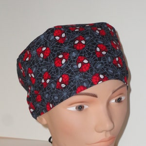 May include: A black scrub hat with a red and white spider-man design. The hat has a tie on the back.