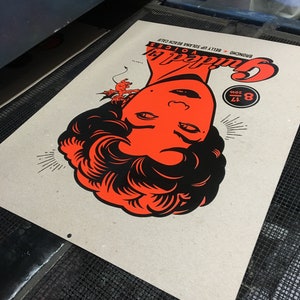 May include: A vintage-style poster with a red and black illustration of a woman's face. The poster is titled "Guilty Pleasures" and has the text "8.12.2019" in a circle. The poster is printed on brown paper.