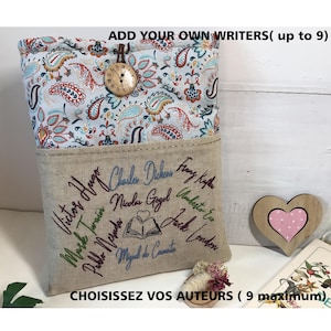 Pode incluir: Capa de livro personalizada com uma parte superior estampada com padrão paisley e uma parte inferior bege. A capa apresenta nomes de autores bordados e o texto "ESCOLHA SEUS AUTORES (9 no máximo)". Um coração de madeira e um pequeno buquê de flores também estão presentes.