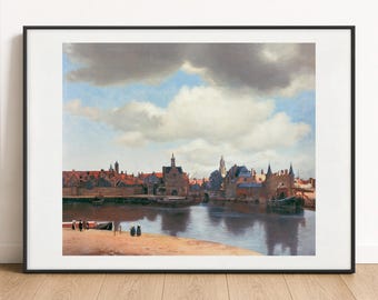 May include: A framed print of Johannes Vermeer's View of Delft, featuring a cityscape with red-roofed buildings, a calm river, and a sandy bank with small figures under a large, cloudy blue sky, presented in a thin black frame.