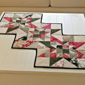 May include: A white sofa with two red and green patterned cushions and a green cushion. A white coffee table with a red, green and white patterned table runner.