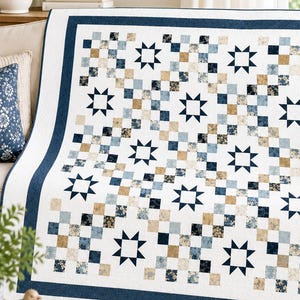May include: A rectangular quilt featuring a repeating pattern of dark blue eight-pointed stars interspersed with a grid of small squares in shades of navy blue, light blue, tan, and white, all framed by a solid dark blue border on a white background.