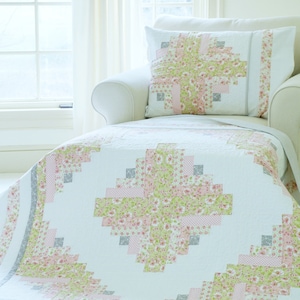 Puede incluir: Un sillón blanco con un cojín estampado floral y un edredón a juego. El edredón y el cojín presentan un diseño floral rosa y verde con detalles grises. El edredón está sobre la silla, creando un ambiente acogedor y acogedor.