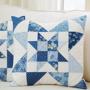 Peut inclure: Un oreiller patchwork bleu et blanc avec un motif d'&eacute;toile. L'oreiller est fait de diff&eacute;rents tissus avec des motifs floraux et g&eacute;om&eacute;triques.