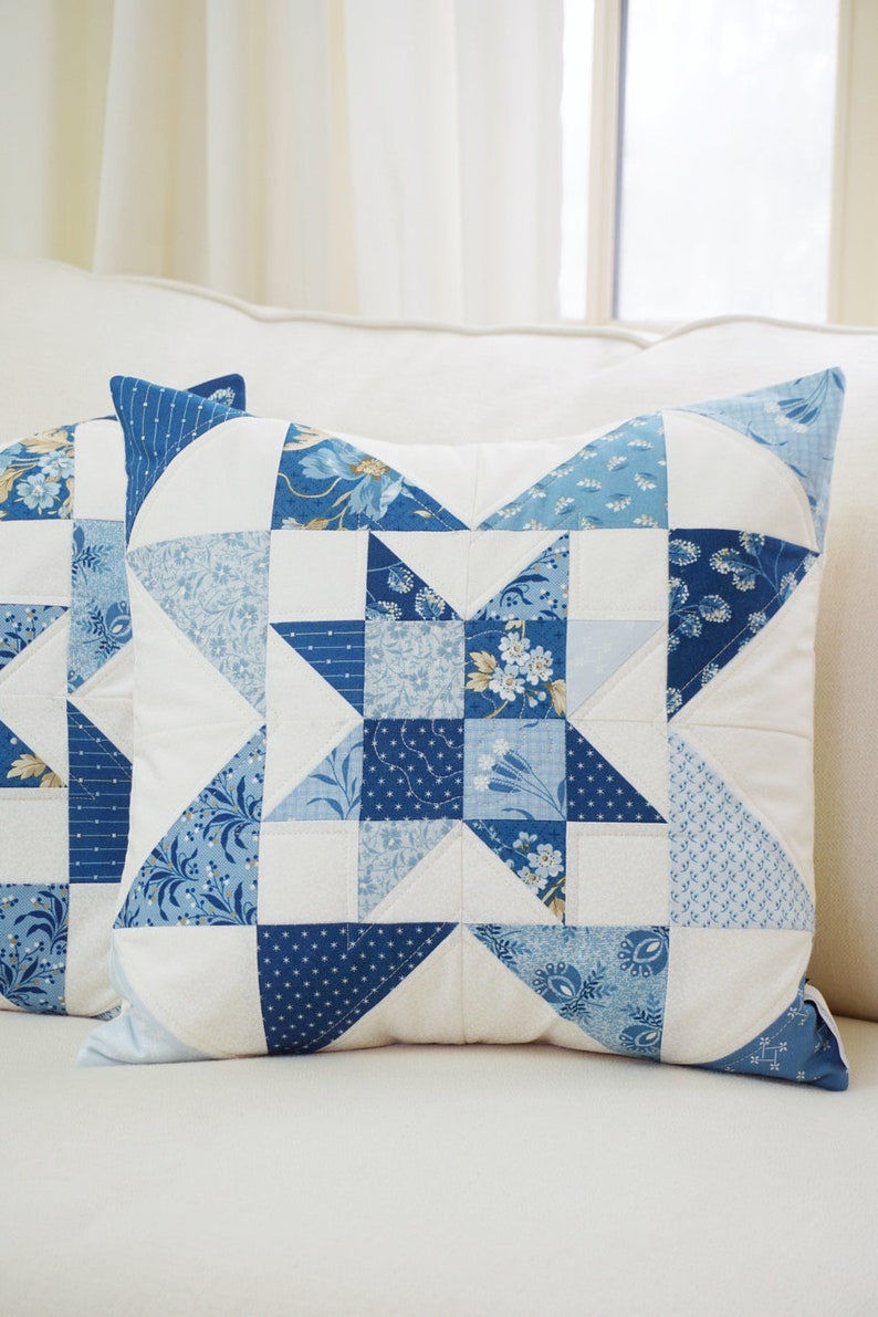 Peut inclure: Un oreiller patchwork bleu et blanc avec un motif d'&eacute;toile. L'oreiller est fait de diff&eacute;rents tissus avec des motifs floraux et g&eacute;om&eacute;triques.