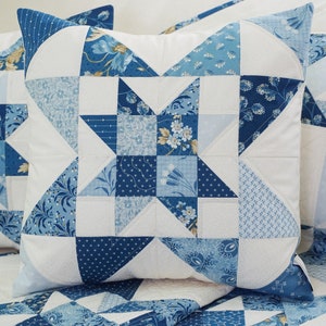 Peut inclure: Un oreiller bleu et blanc en patchwork avec un motif d'&eacute;toile. L'oreiller est fait de diff&eacute;rents tissus avec des motifs floraux et g&eacute;om&eacute;triques.