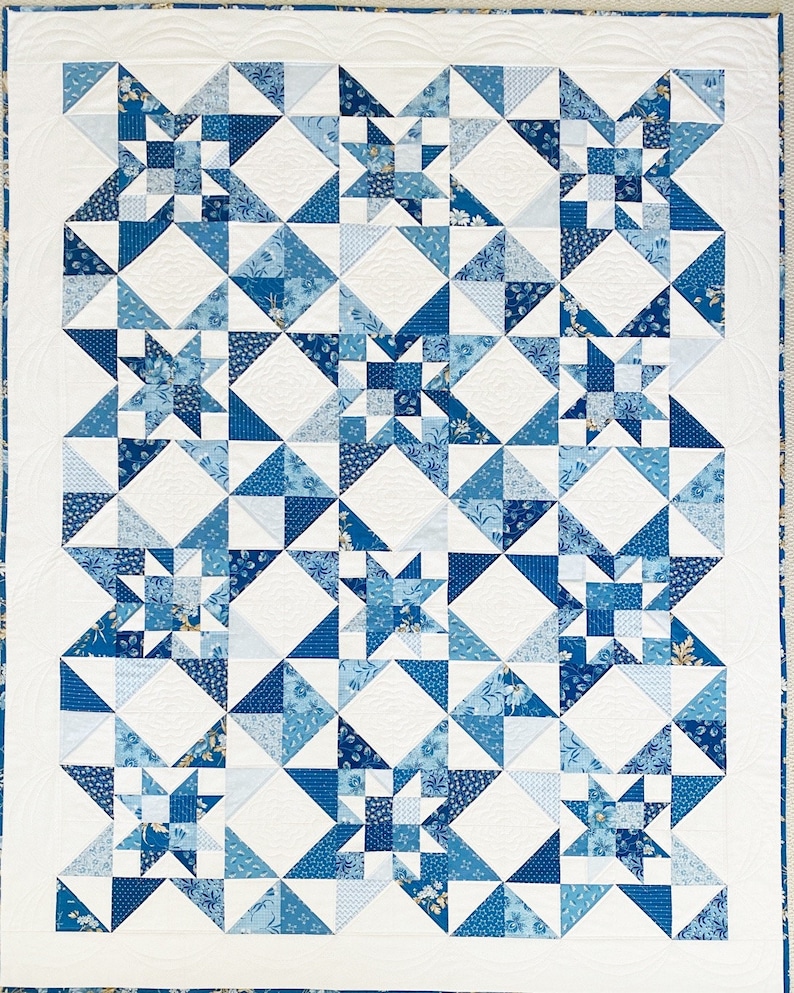 Peut inclure: Une courtepointe blanche avec un motif g&eacute;om&eacute;trique bleu et blanc. La courtepointe est compos&eacute;e de carr&eacute;s et de triangles et pr&eacute;sente un motif d'&eacute;toiles r&eacute;p&eacute;t&eacute;.