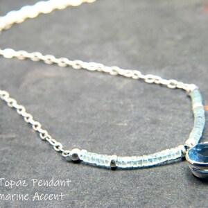 May include: A silver chain necklace with a blue topaz pendant and aquamarine beads. The pendant is a round, faceted stone set in a silver bezel.