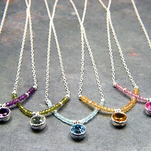 May include: Five silver necklaces with different coloured gemstone pendants. Each necklace features a row of small beads in a coordinating colour. The pendants are amethyst, peridot, aquamarine, citrine, and pink sapphire.