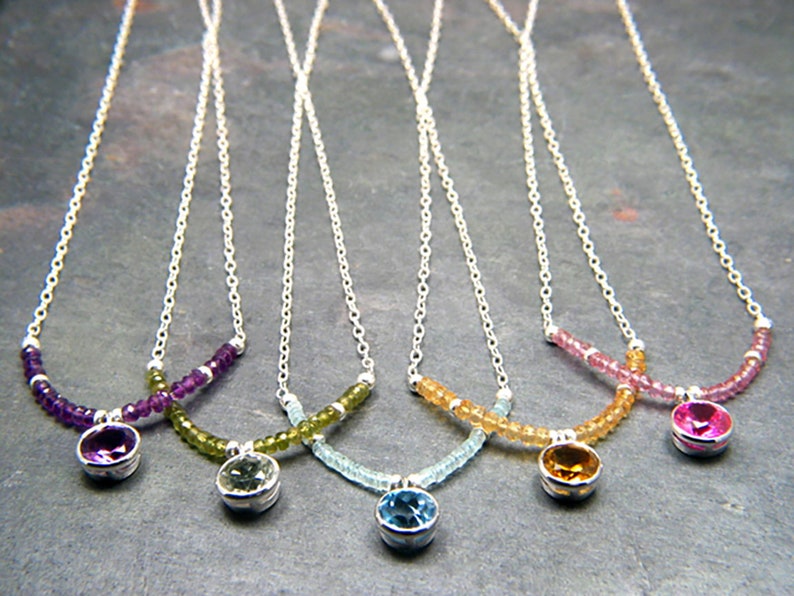 May include: Five silver necklaces with different coloured gemstone pendants. Each necklace features a row of small beads in a coordinating colour. The pendants are amethyst, peridot, aquamarine, citrine, and pink sapphire.