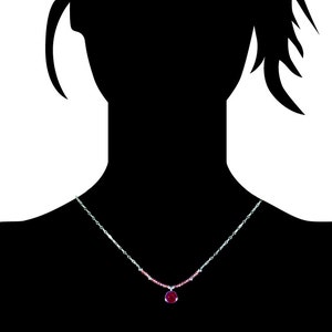 May include: A silver chain necklace with a small, round, red gemstone pendant.