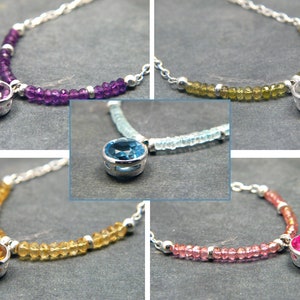 May include: Five silver necklaces with different coloured gemstones. Each necklace features a round gemstone pendant with a silver setting. The gemstones are amethyst, aquamarine, citrine, pink tourmaline, and clear.
