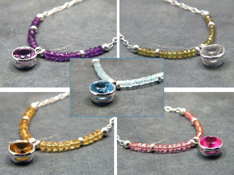 May include: Five silver necklaces with different coloured gemstones. Each necklace features a round gemstone pendant with a silver setting. The gemstones are amethyst, aquamarine, citrine, pink tourmaline, and clear.