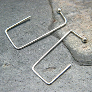 May include: A pair of silver hoop earrings with a small ball at the end of each hoop.