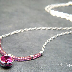 May include: A silver chain necklace with a pink topaz gemstone pendant and pink topaz beads. The pendant is set in a silver bezel.