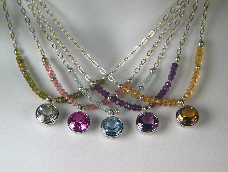 May include: Five silver necklaces with different coloured gemstone beads and matching pendant charms. The necklaces feature green, pink, blue, purple, and yellow gemstones.