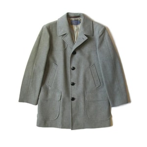 May include: A light gray wool coat with a classic design. The coat features a notched collar, three black buttons, two front pockets, and a tailored fit. The coat is a mid-length style, suitable for cooler weather.