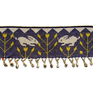 May include: A beaded headband with a fringe of white beads and a design of two white rabbits running through yellow flowers on a blue background.