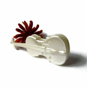May include: A white ceramic violin figurine. The violin has a detailed design and is a decorative piece.