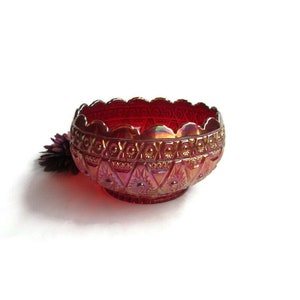 May include: A red glass bowl with a geometric pattern. The bowl has a scalloped edge and a iridescent finish.