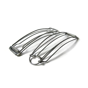 May include: Two metal hair barrettes. Each barrette features a series of curved, thin metal wires held together by a rectangular clasp. The barrettes are a dark, metallic color and are set against a white background.
