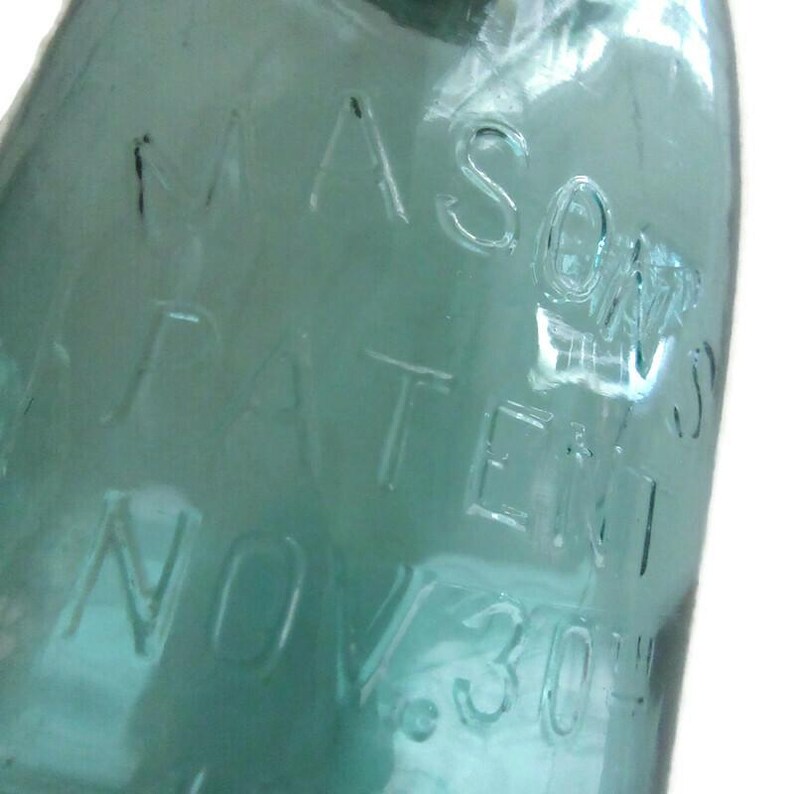 May include: A vintage green glass Mason jar with the text "MASON'S PATENT NOV 30 1858" embossed on the side.